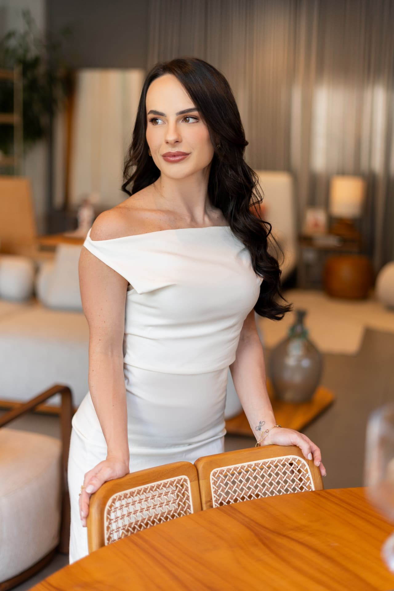 Dra. Ana Henriques, médica, em vestido branco em ambiente claro e acolhedor