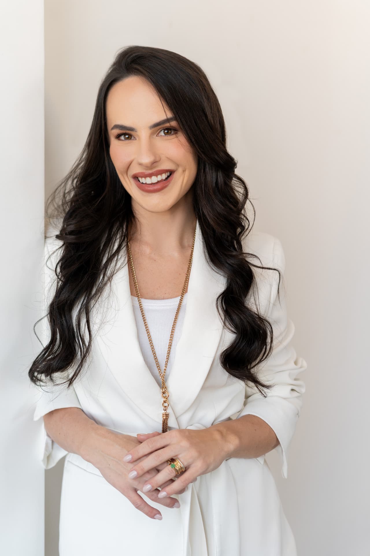 Dra. Ana Henriques sorrindo, de blazer branco, retrato profissional